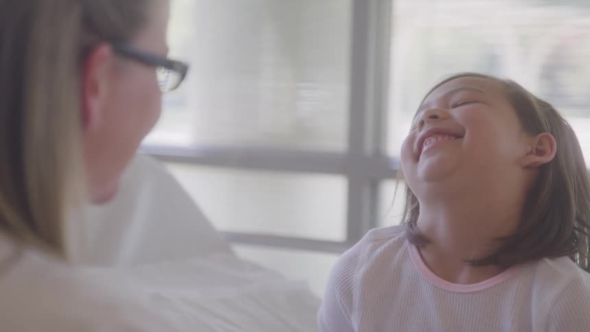 Child smiles broadly while talking to a woman wearing glasses