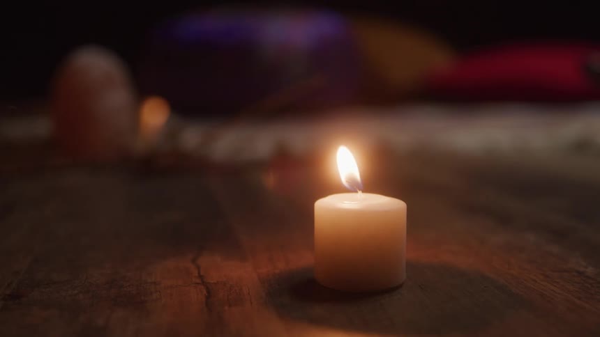 Lit candle on a wooden surface
