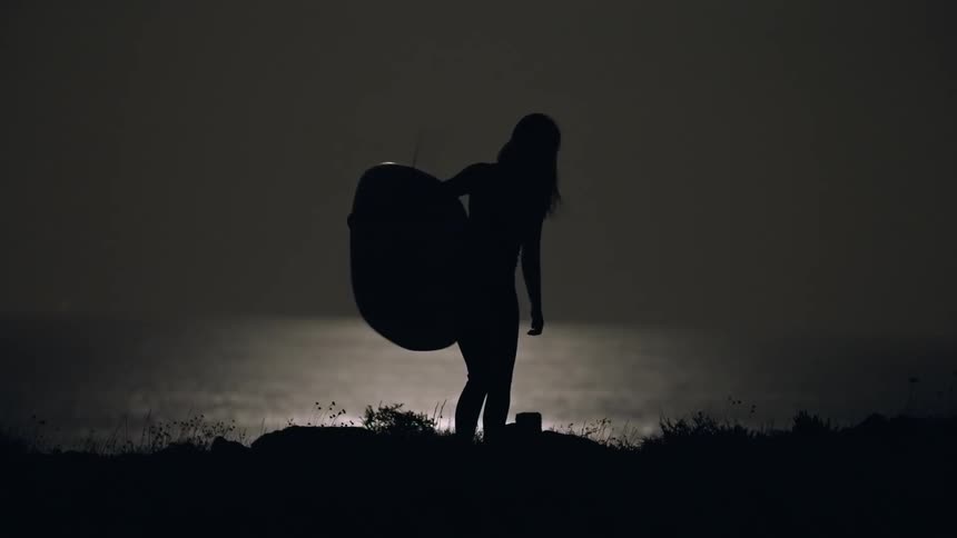 A woman with a surfboard walks back and forth to the beach