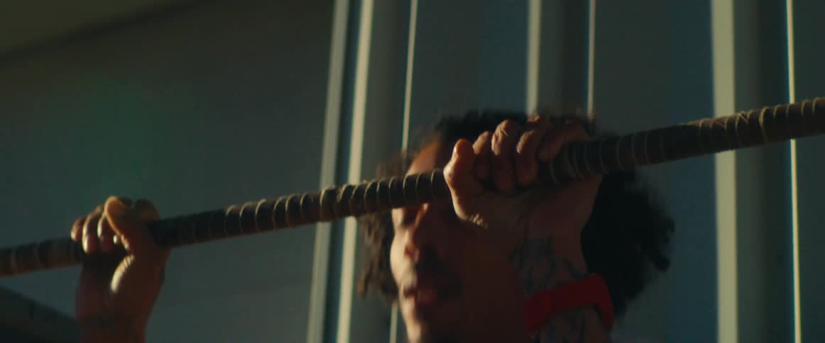 A tattooed person performs pull ups on a bar