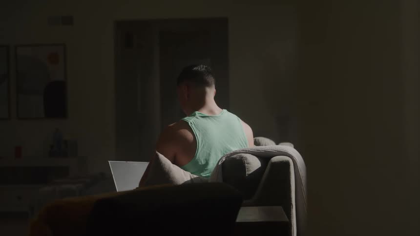 A man is using his laptop on the couch