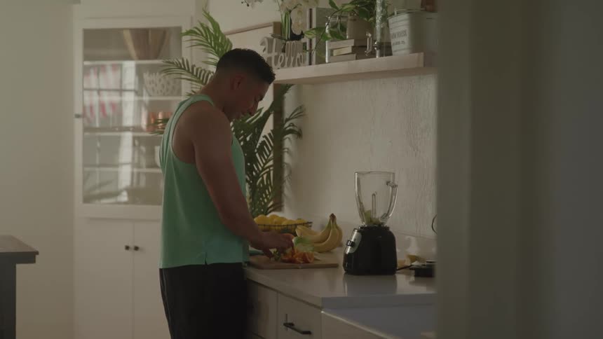 A man makes a smoothie in the kitchen