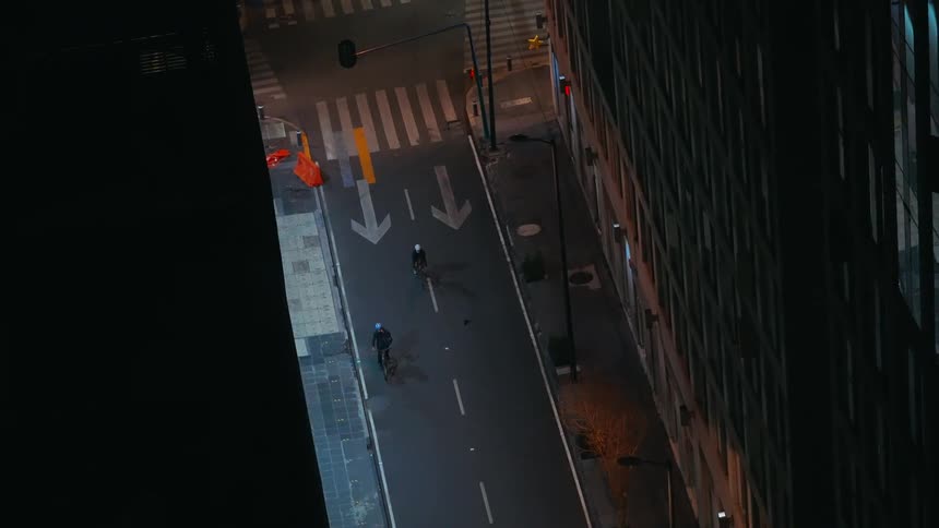 Two people ride bikes on the street at night