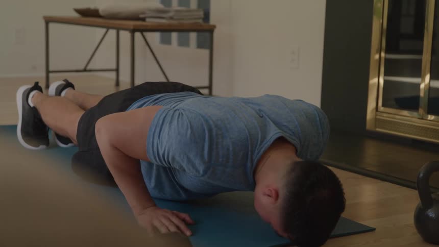 Man doing pushups on a mat indoors