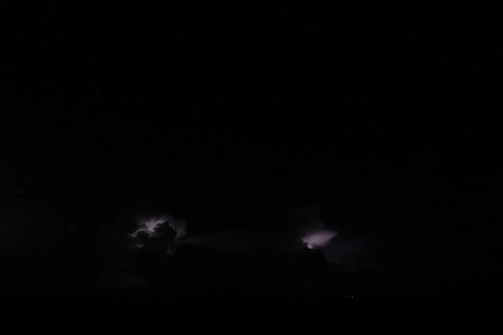 Lightning illuminates massive storm clouds in the night sky