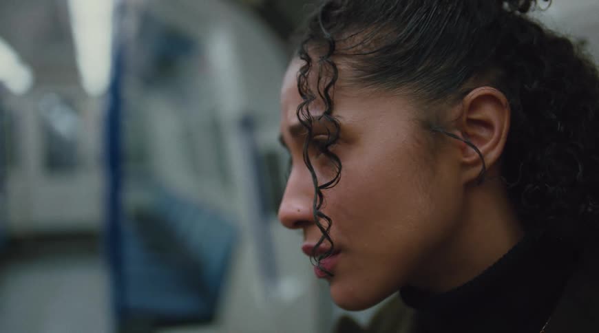 A woman sits alone on a train looks sad