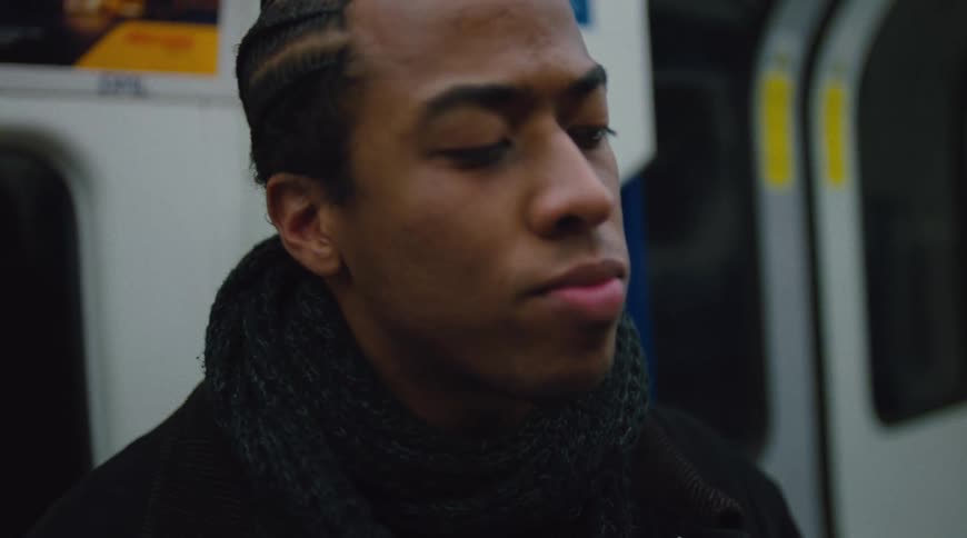 Man sits on a train with a pensive expression