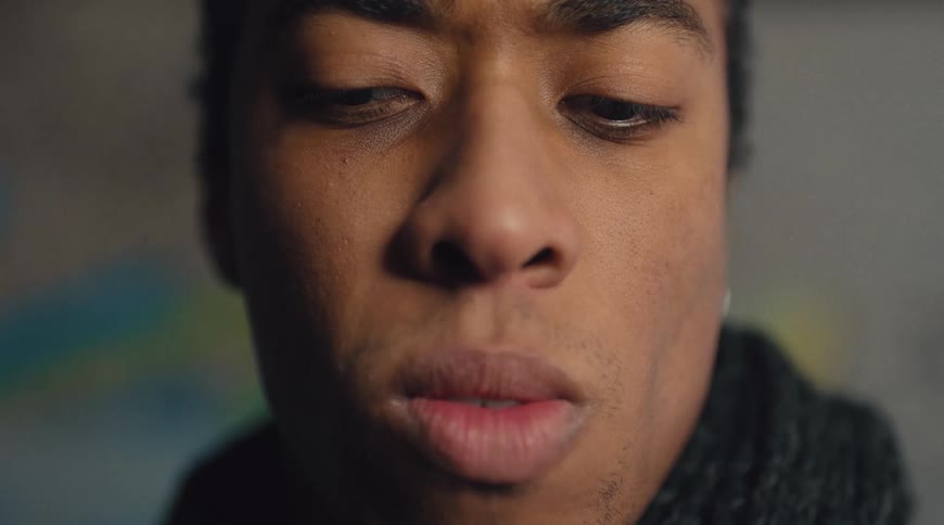 A young mans face is shown as he looks around and then stares directly ahead