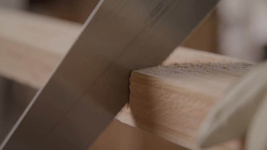 Closeup of a hand saw cutting a wooden plank