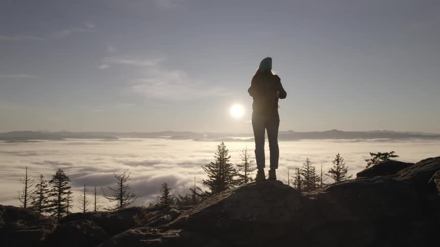 A girl stands above the clouds