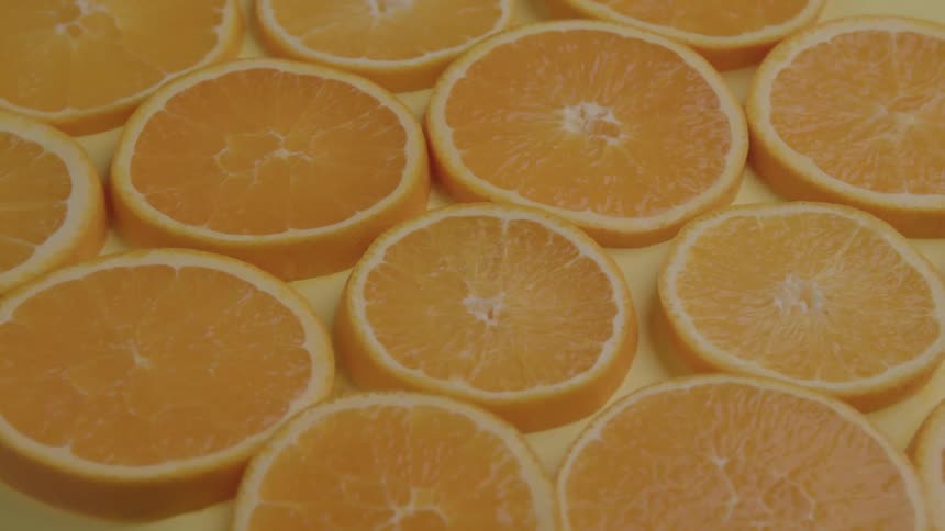 Orange slices arranged side by side on a yellow surface