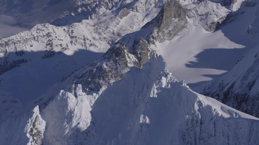 Snowcovered mountain range with sharp peaks and shadowed valleys
