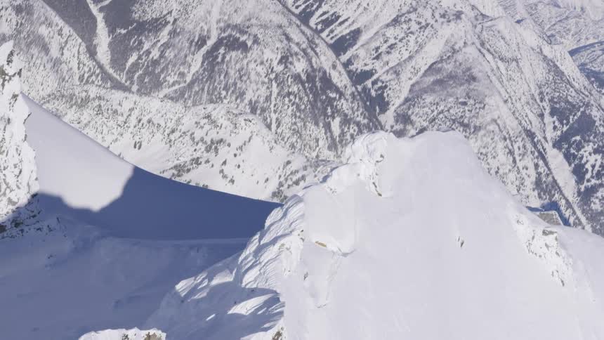 An aerial view captures the vast pristine snow covered peaks and valleys of a mountainous landscape
