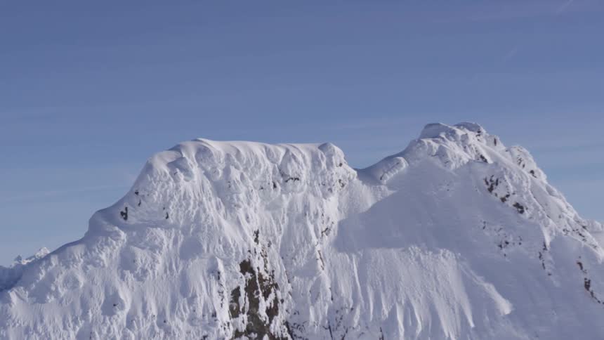 A mountain range covered in snow during the winter season at midday