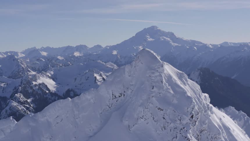 Snowcovered mountain range with peaks in the background under a clear sky
