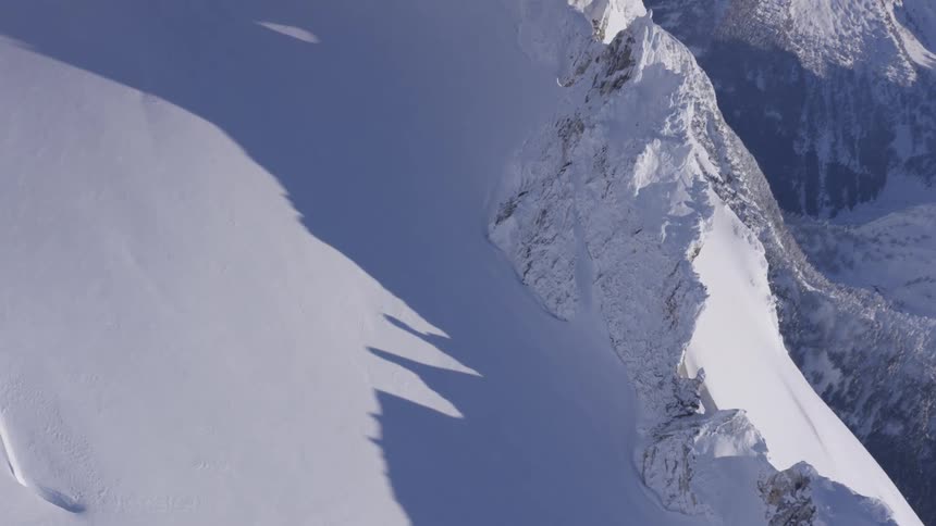 Snowcovered mountain wall casting shadows on the slope
