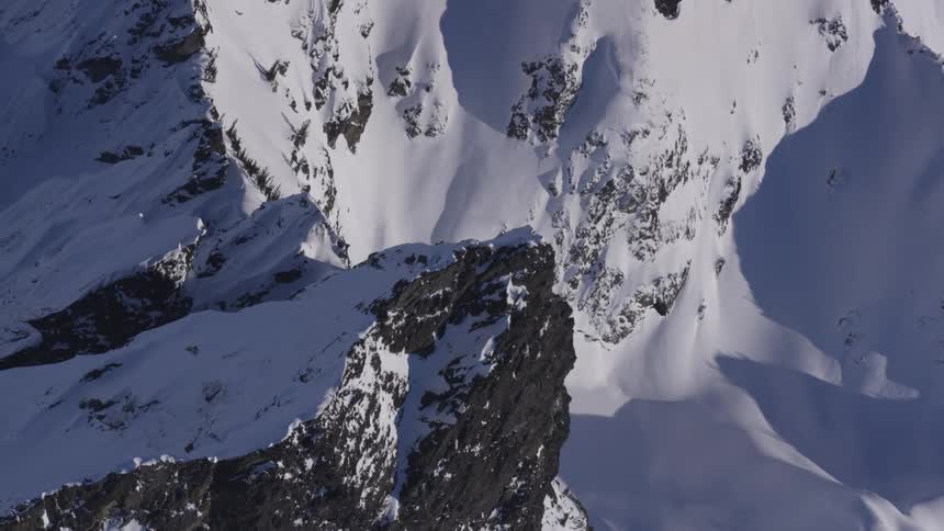 A snowcovered rugged mountain range under a sunny winter sky