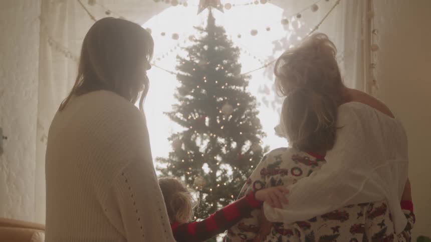 Grandmother with two grandchildren and daughter in front of a happy christmas tree
