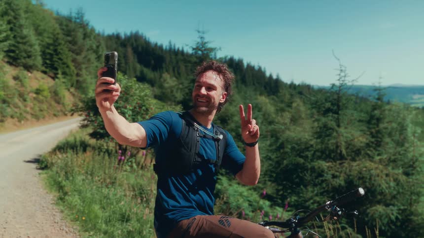 A man takes a selfie on his mountain bike in a forest