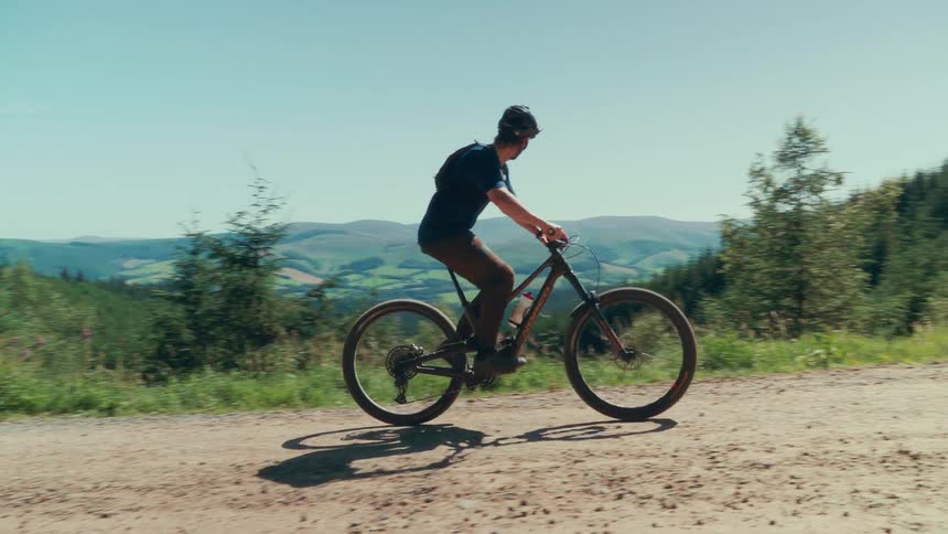 A man rides a mountain bike on a hillside dirt road