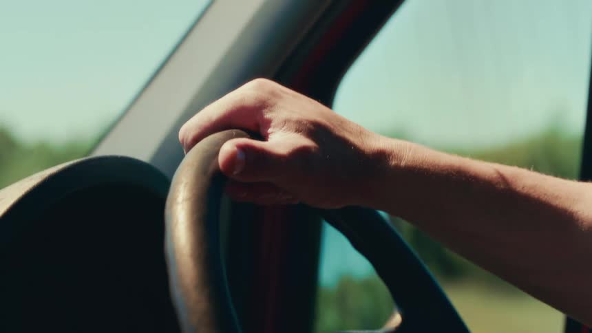 The video shows a closeup shot of a persons hands gripping a steering wheel the person is driving a vehicle during the daytime the video has a watermark that reads filmsupply