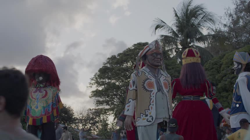 People watch giant puppets dressed in traditional costumes