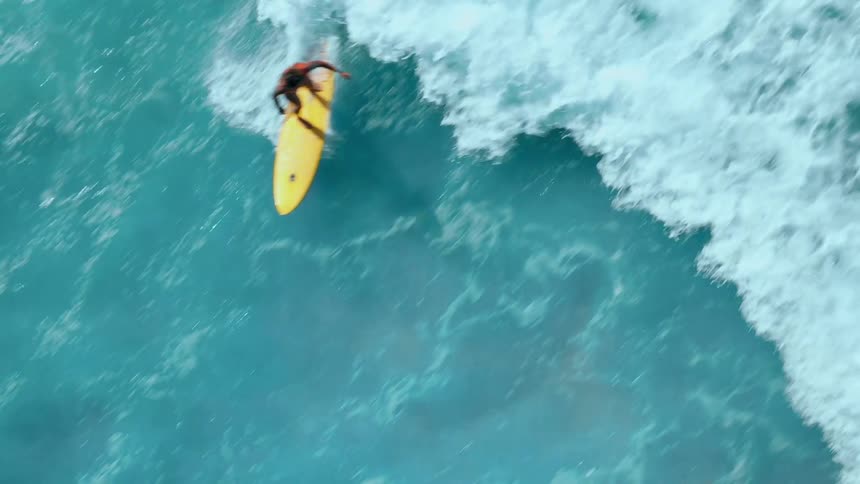 Surfer performs a maneuver on a wave with a yellow board