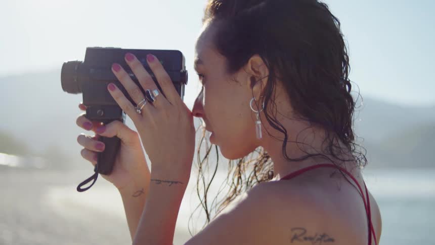 The face of a young woman on the beach holding a photography camera to her face