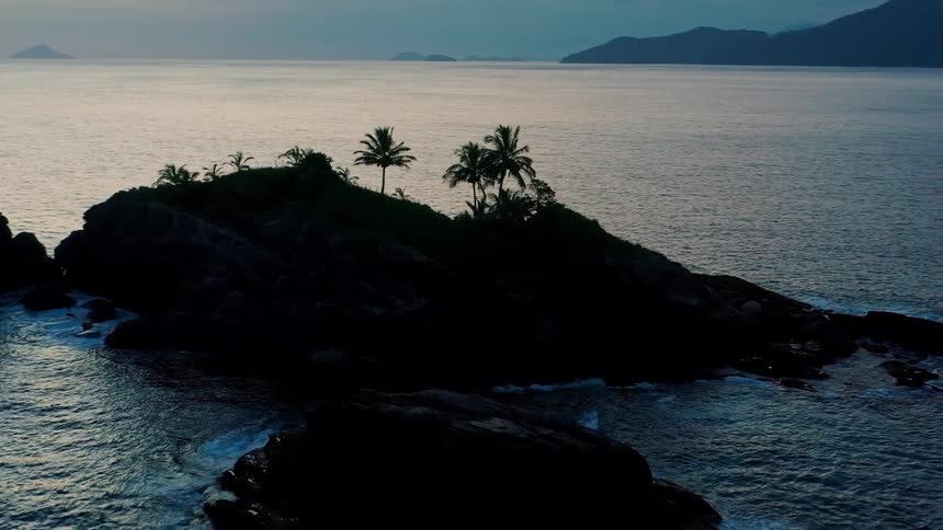 Palm trees stand on an island under a cloudy red sky