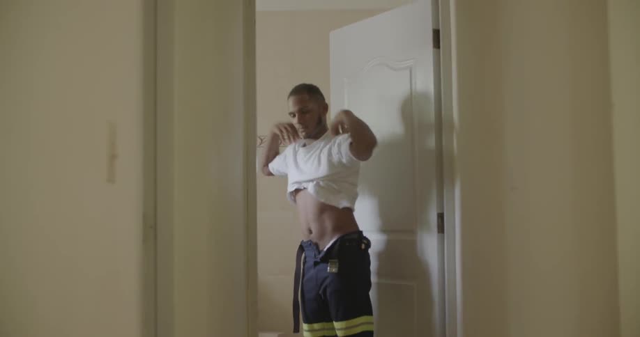A man is putting on a t-shirt