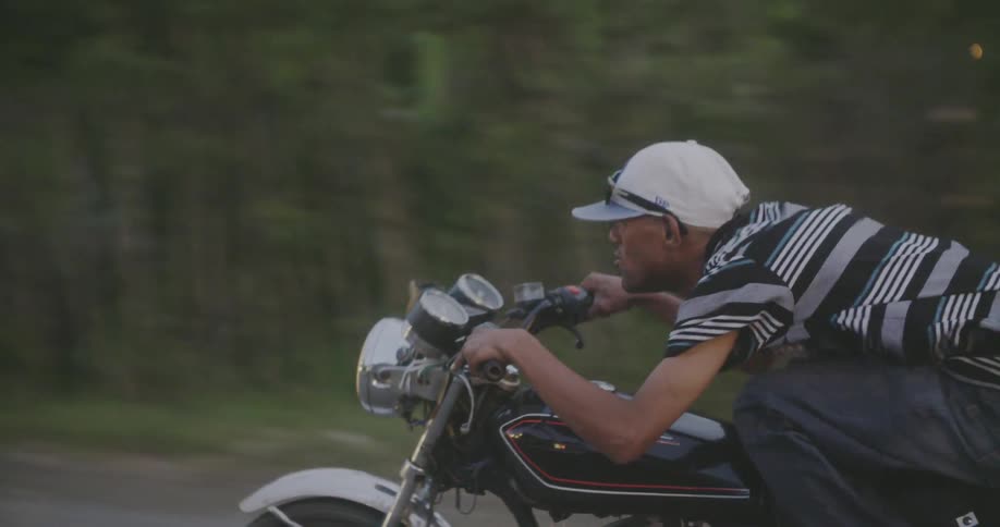 A man leans into the handlebar of a speeding motorcycle