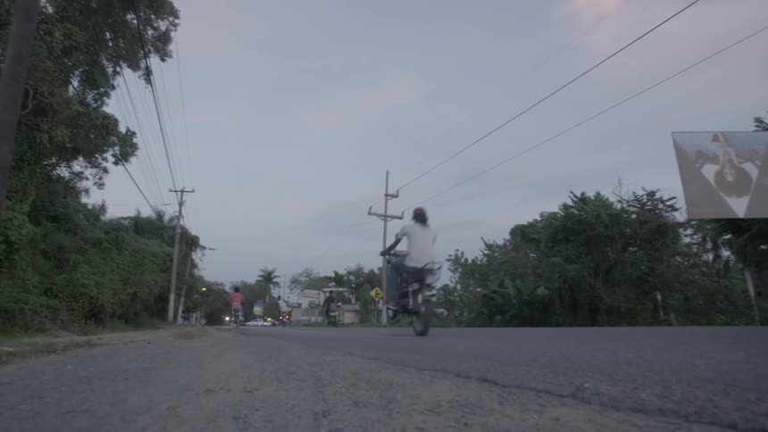 Men ride motorbikes against traffic