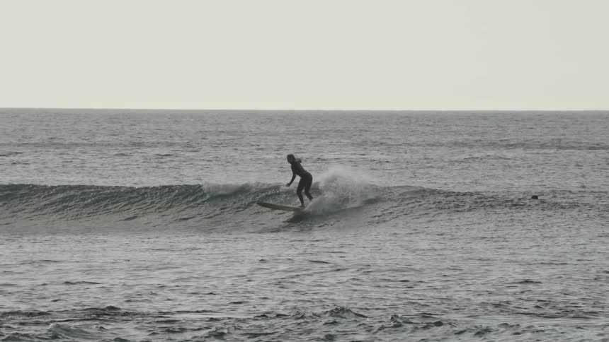 Three people surfing on the sea in the evening