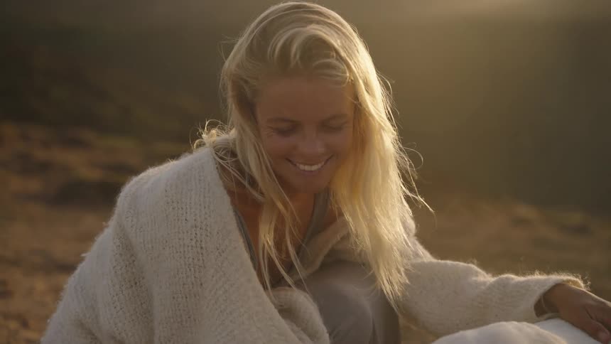 Blonde woman crouches and smiles while petting a dog near foggy mountainous terrain