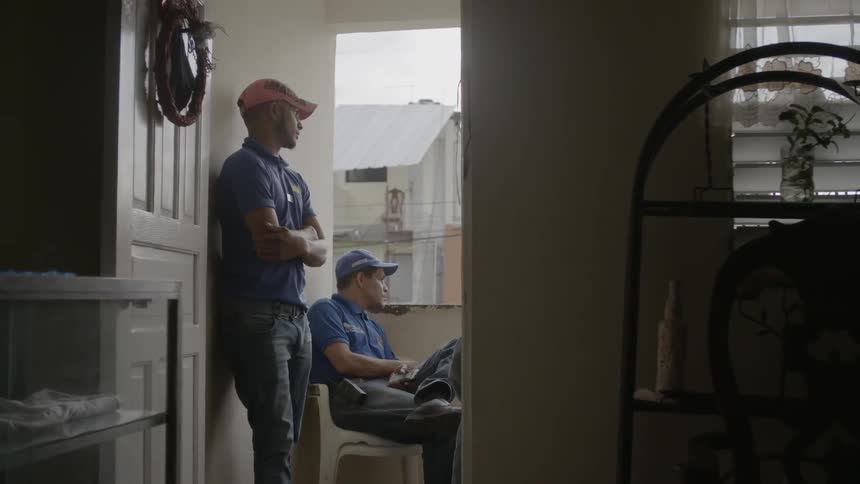 Two men stare out from a balcony