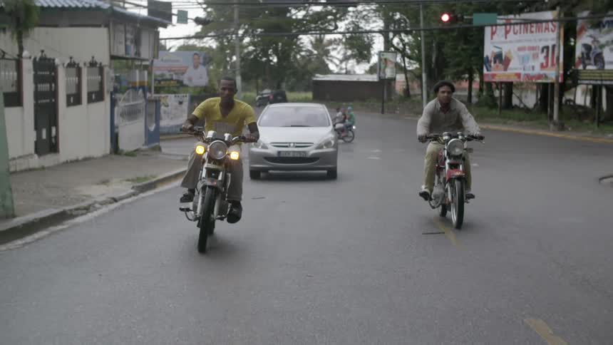 Two men are riding motorcycles and doing wheelies