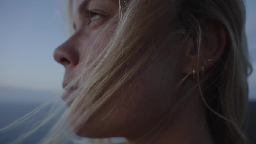 Closeup of a womans face with strands of hair blowing in the wind