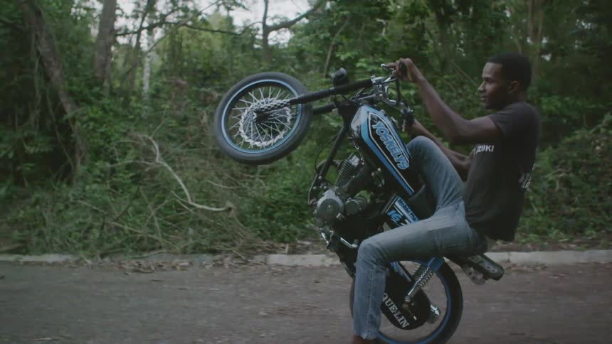 A man performs a wheelie on a motorcycle