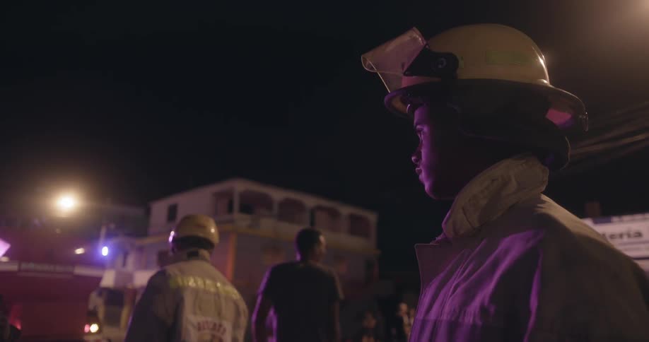 Flashing lights shine on firefighters at night