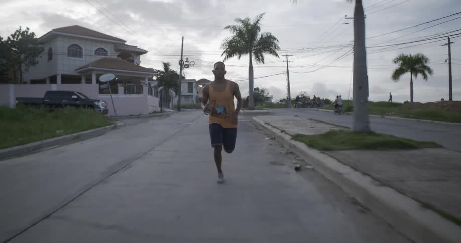 A man is jogging down the middle of a street