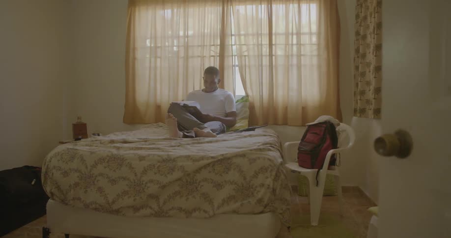A man flips through papers while sitting on a bed