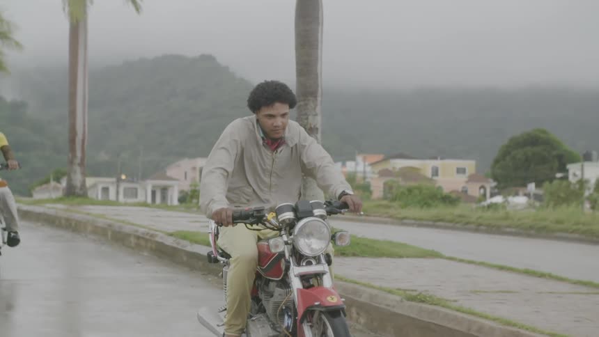 Motorcyclists ride on a street while it rains