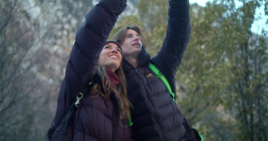 Couple in winter clothing looks upward during a mountain hike
