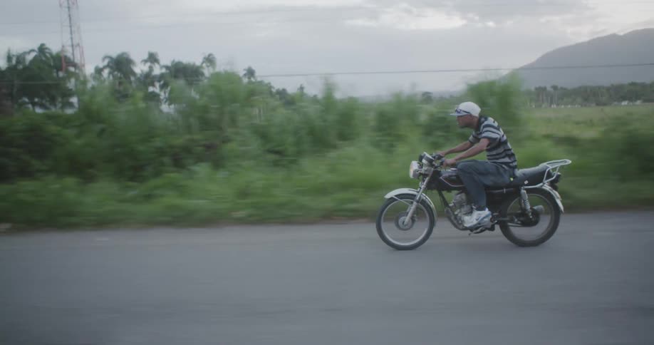 Man riding motorcycle down street on cloudy day