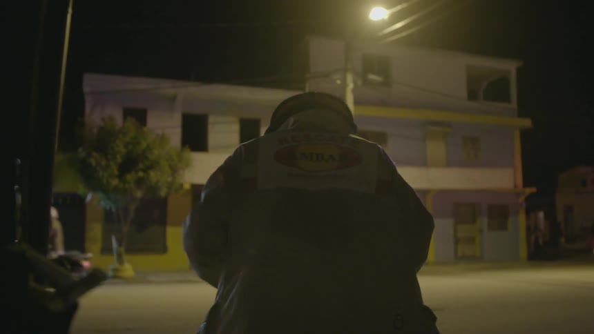 A firefighter stands on a street near flashing lights