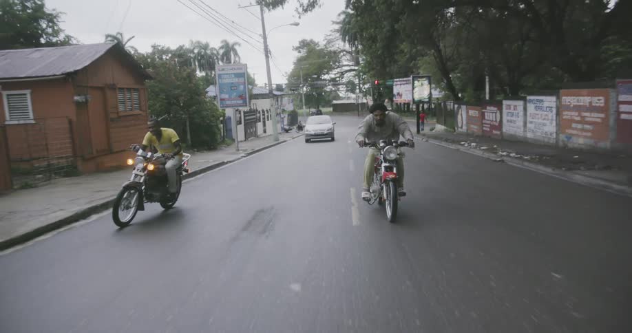 Motorcycles move past a car on the road