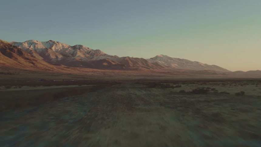 A large area of badland with a mountainous background at sunrise