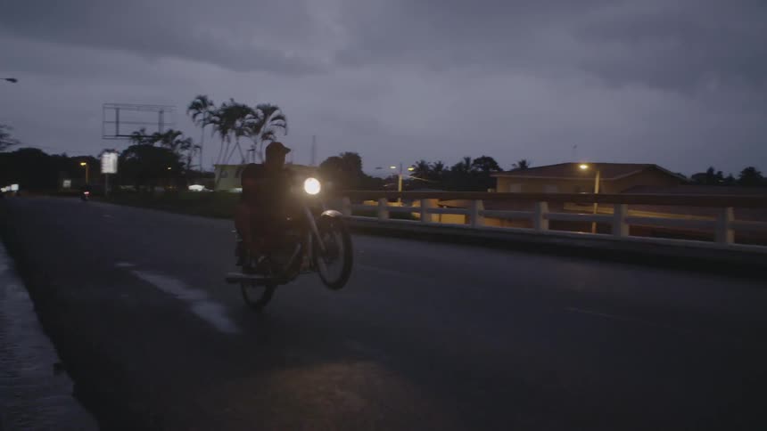 Man doing wheelie on motorcycle on street at night
