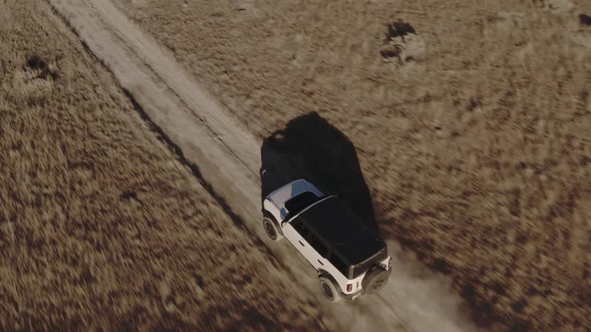 White suv driving on a dirt road in an arid area