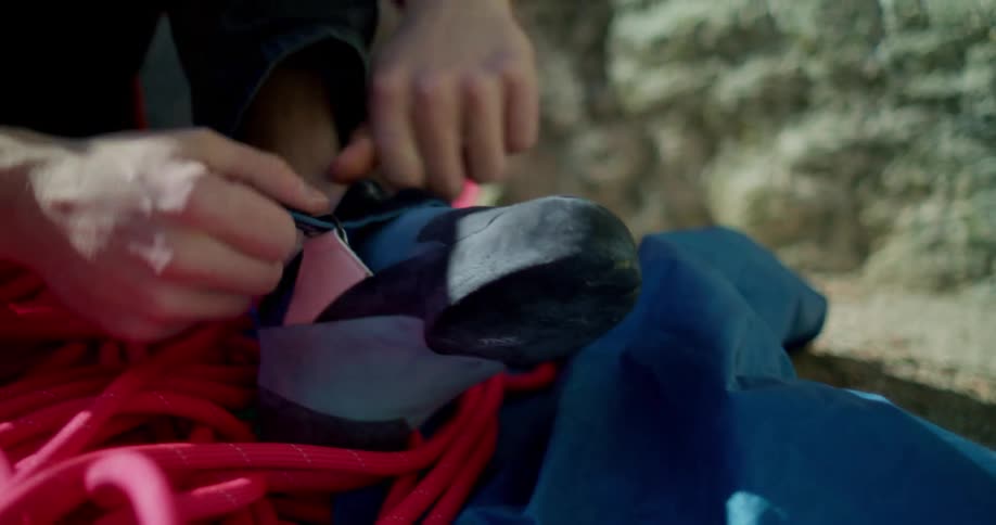 Person putting on a climbing shoe next to a red rope